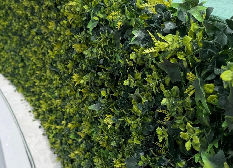 Muro verde de follaje artificial instalado por Game Turf sobre un muro curvo.