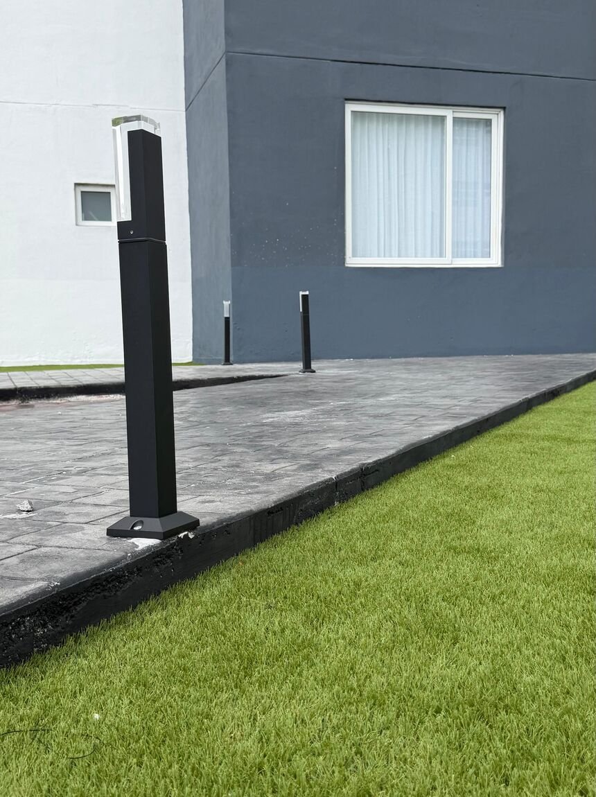 Franja de pasto sintético Game Turf junto a un andador de concreto estampado en un desarrollo residencial.