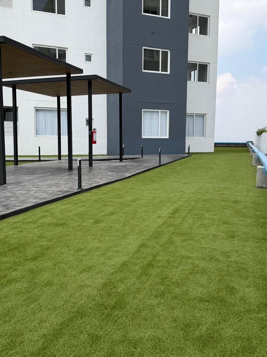 Pasto sintético Game Turf en el acceso de un edificio de departamentos, junto a la palapa y el andador.
