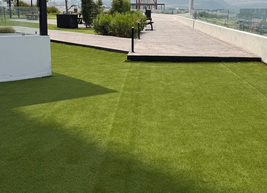 Roof garden con pasto sintético Game Turf sobre losa, con andador y vista a la ciudad.
